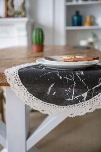 Detail of black marble print table runner with elegant white lace borders and fabric texture