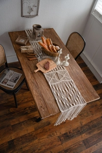 Detail of bohemian hand-woven macrame table runner with geometric patterns and fringe