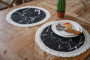 Close-up of black marble print placemat with delicate white lace edges on wood table