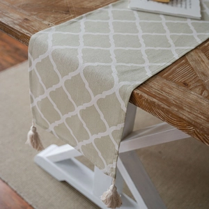 Olive green table runner with white geometric clover patterns and tassel fringe edge