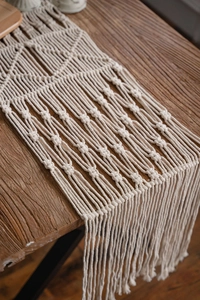 Detailed close-up of handmade Bohemian macrame table runner with cotton tassels on wood