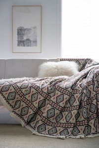 Close-up of bohemian geometric jacquard sofa cover with fringe details and thick texture