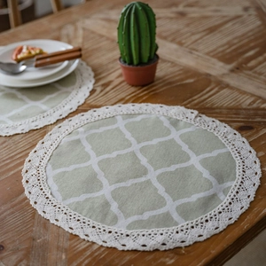 Pastel green geometric round placemat with elegant white lace trim on wooden dining table