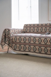 Detail of bohemian sofa cover with red and blue geometric patterns and white tassels