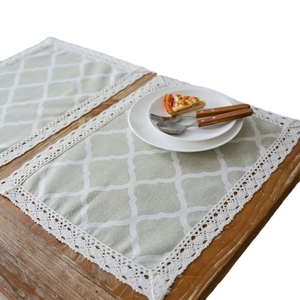 Set of two light green placemats with white grid patterns and elegant lace edges
