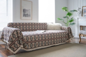 Detail of bohemian geometric jacquard sofa cover with white fringe and ethnic weaving