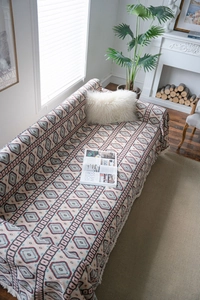 Detail of bohemian geometric jacquard sofa cover with fringe tassels and retro patterns