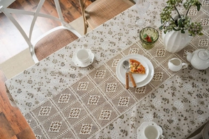 Close-up of rustic beige tablecloth featuring floral prints and hollowed-out crochet lace trim