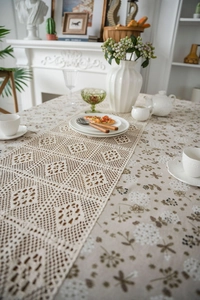 Detail of beige floral tablecloth with elegant cream white hollow lace table runner set