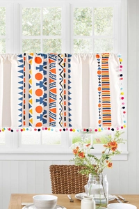 Detail of bohemian geometric kitchen curtain with colorful pom-pom trim on a window
