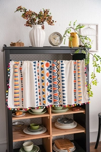 Detail of colorful pompom trim and geometric prints on Nordic style short cafe curtains