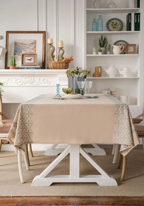 Close-up of blue geometric diamond embroidery on linen tablecloth over a wooden dining table