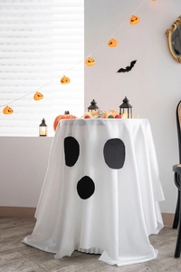 Detail of Halloween tablecloth with cute ghost face design and festive pumpkin decor