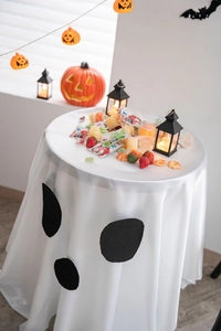 Detail of Halloween ghost face tablecloth with white satin texture and pumpkin decor