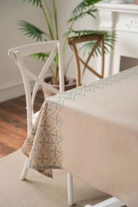 Detail of blue geometric diamond embroidery on premium off-white linen tablecloth