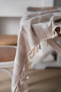 Detailed macro view of cream embroidery stripes and tassels on linen tablecloth