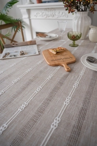 Detailed view of white chain embroidery on beige linen texture tablecloth fabric