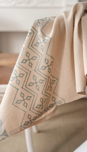 Detail of linen tablecloth with teal geometric embroidery and natural woven texture