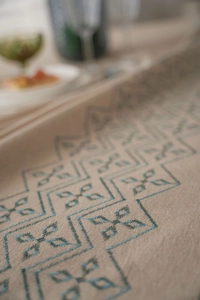 Close-up detail of blue geometric floral embroidery on a premium beige linen tablecloth