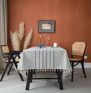 Detail of grey striped rectangle tablecloth with off-white tassel trim and cotton-linen texture