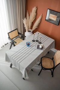 Close-up of gray cotton linen tablecloth featuring black stripes and cream tassel trim detail