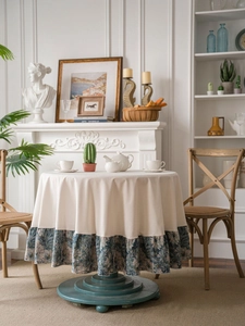 Close-up of French pastoral round tablecloth with blue floral ruffles and beige linen fabric
