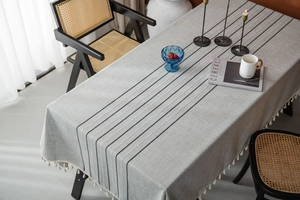 Detailed texture of grey linen tablecloth with black stripes and white fringe tassels