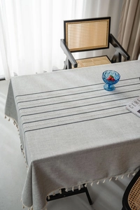 Detail of grey tablecloth showing stripe embroidery and decorative fringe edges