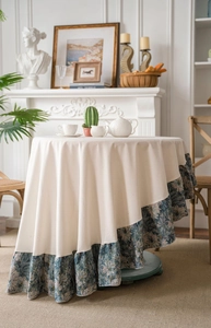 Detail of round French vintage tablecloth featuring cream thick fabric and blue floral ruffle
