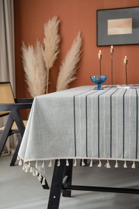 Detailed macro view of gray striped tablecloth with white embroidery and cream tassels