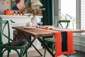 Close-up of Halloween orange and black striped table runner with knit fringe on wood