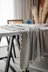 Detail of grey striped tablecloth with elegant tassels and rustic linen texture