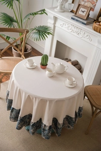 Detail view of round thick cotton linen tablecloth with vintage blue floral ruffled edge