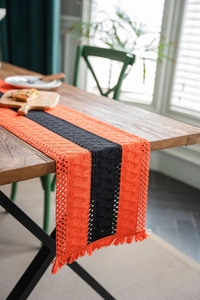 Detail of orange and black striped table runner with handmade tassels and crochet edges