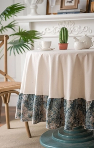 Detail view of cream tablecloth featuring vintage floral brocade ruffles on the round edge