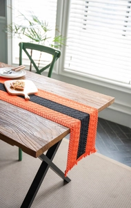 Detail of orange and black striped knitted table runner with fringes for Halloween party