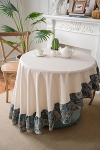 Detail of round tiered tablecloth featuring cream fabric and blue floral jacquard ruffles