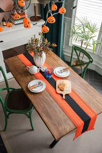 Close-up of orange and black striped knitted Halloween table runner with fringed edges