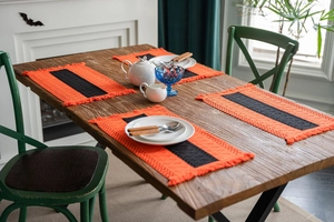Close-up of 4-piece set of orange and black striped woven placemats with fringe details
