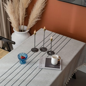 Gray striped tablecloth with white embroidery and tassels in a modern home dining setting