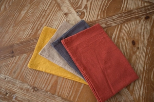 Folded Nordic washed cotton table napkins in mustard yellow, khaki, grey and rust red colors