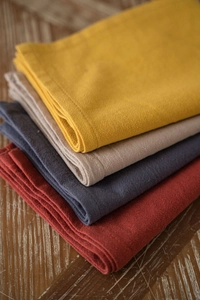 Stack of folded washed cotton napkins with textured natural fabric in four earthy tones