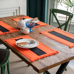Set of 4 orange and black striped woven placemats with tassels for Halloween dining decor