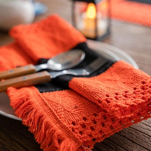 Halloween orange and black knitted table mat with fringe on a wooden dining table