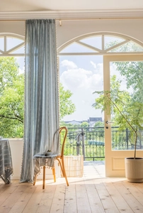 Detail of light blue striped curtain with tassels in a bright sunlit interior scene