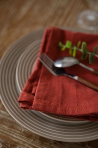 Close-up of dark red washed cotton table napkin showing fabric texture and fine stitching