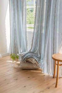 Detail of light blue curtains with beige tassels and vertical geometric patterns