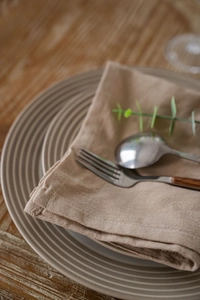 Macro view of textured brown cotton napkin with ceramic plates on a wooden dining table