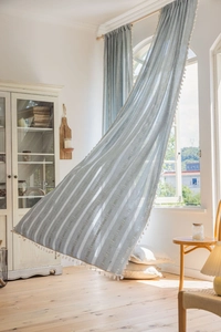 Detailed view of light blue striped curtains featuring elegant cream white tassel edge fringe