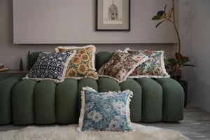 Selection of Jacquard throw pillows with tassel edges on a green sofa in home setting